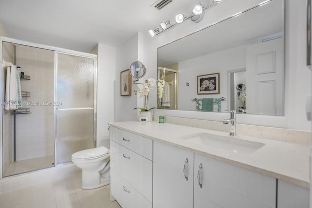 bathroom with tile patterned floors, vanity, toilet, and a shower with shower door