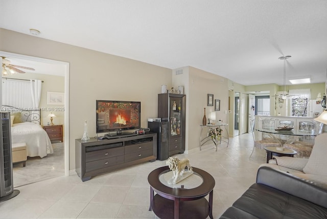 living area featuring light tile patterned flooring, visible vents, and ceiling fan