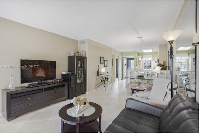 living area featuring light tile patterned flooring, visible vents, and a textured ceiling