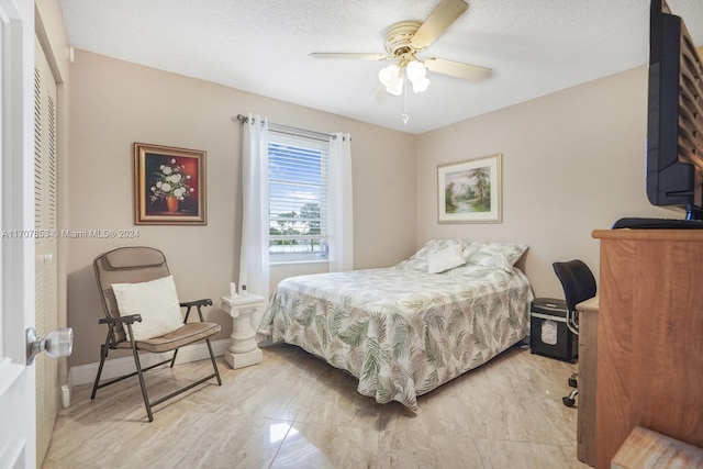 bedroom with ceiling fan and a textured ceiling