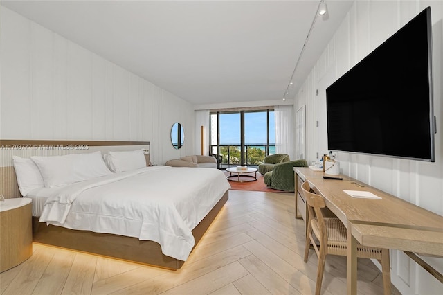 bedroom with track lighting and light parquet flooring