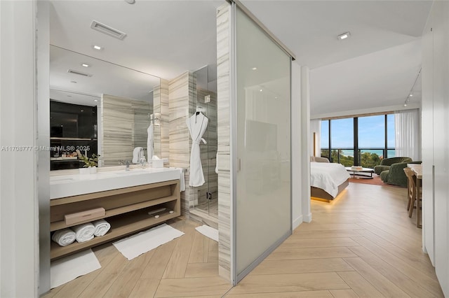 bathroom with a shower with shower door, vanity, and parquet floors