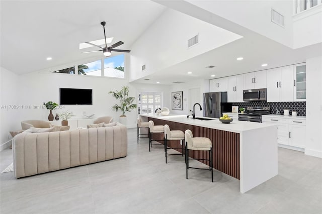 kitchen featuring high vaulted ceiling, a kitchen breakfast bar, sink, an island with sink, and stainless steel appliances