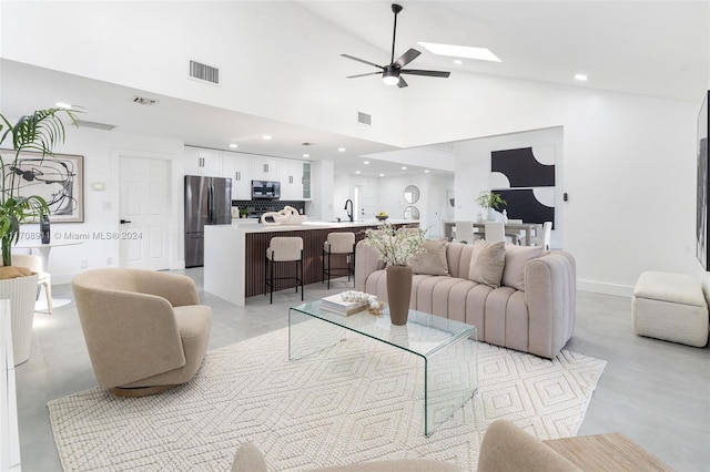 living room featuring high vaulted ceiling, ceiling fan, and sink