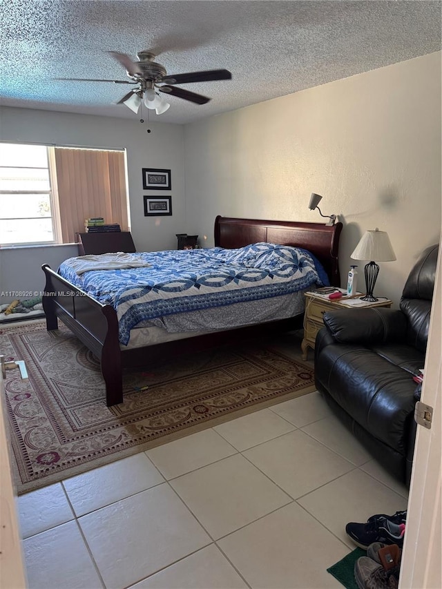 tiled bedroom with ceiling fan and a textured ceiling