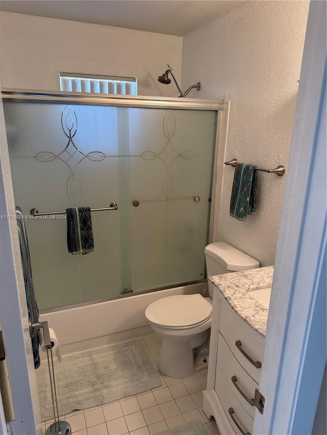 full bathroom featuring shower / bath combination with glass door, tile patterned flooring, vanity, and toilet