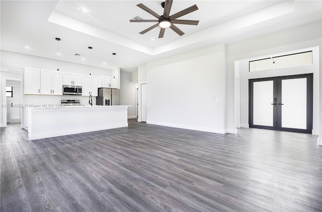 interior space featuring pendant lighting, a center island, white cabinets, dark hardwood / wood-style floors, and appliances with stainless steel finishes