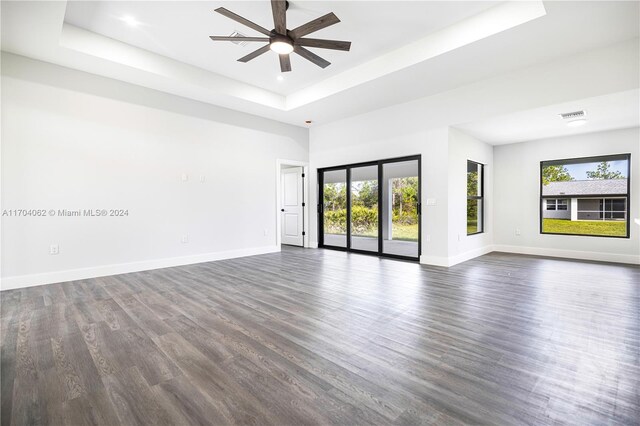 unfurnished room featuring dark hardwood / wood-style flooring, a tray ceiling, and plenty of natural light