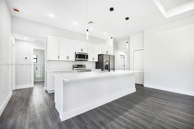 kitchen with white cabinetry, dark hardwood / wood-style flooring, decorative light fixtures, a center island with sink, and appliances with stainless steel finishes