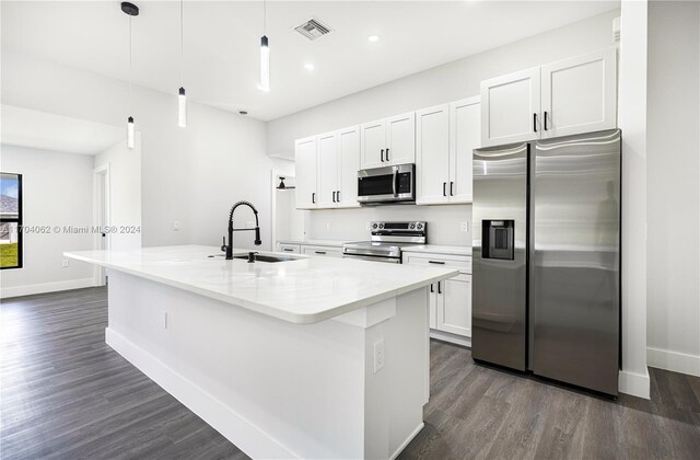 kitchen featuring decorative light fixtures, white cabinetry, an island with sink, and appliances with stainless steel finishes