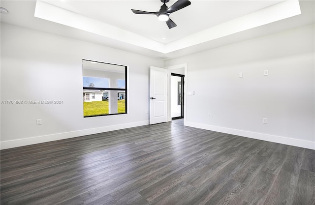 unfurnished room with a raised ceiling, ceiling fan, and dark hardwood / wood-style floors