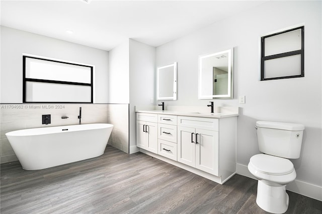 bathroom featuring wood-type flooring, toilet, a bathtub, vanity, and tile walls