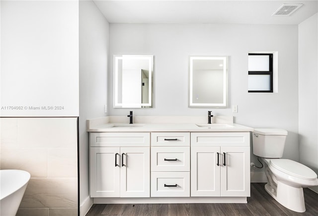 bathroom featuring a washtub, vanity, hardwood / wood-style flooring, and toilet