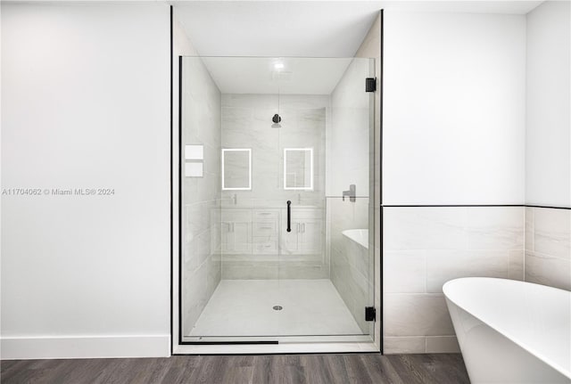 bathroom with plus walk in shower, hardwood / wood-style floors, and tile walls