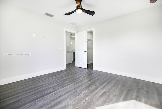 unfurnished bedroom with ceiling fan, dark wood-type flooring, and a closet