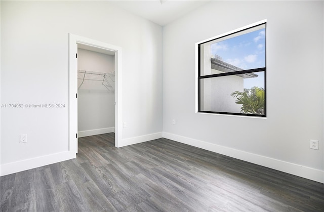 unfurnished bedroom with dark hardwood / wood-style flooring, a walk in closet, and a closet