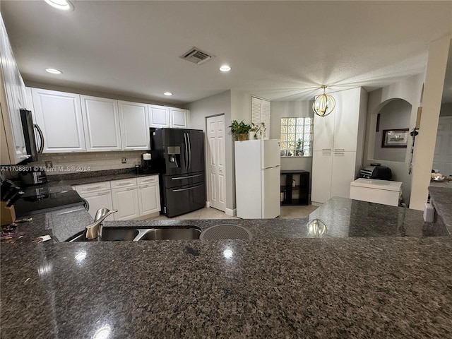 kitchen with white cabinetry, hanging light fixtures, white refrigerator, a chandelier, and black fridge with ice dispenser