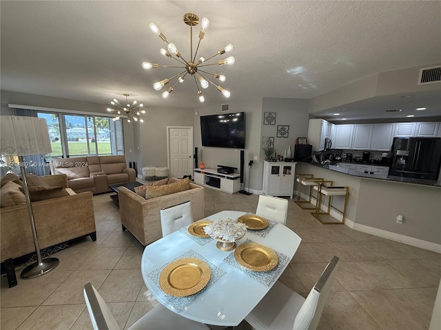 tiled dining space with a chandelier and a textured ceiling