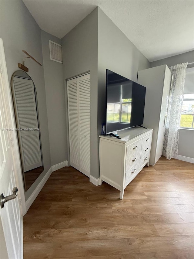 unfurnished bedroom with a textured ceiling, light hardwood / wood-style flooring, and a closet