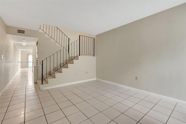 unfurnished room featuring light tile patterned floors, visible vents, baseboards, and stairs