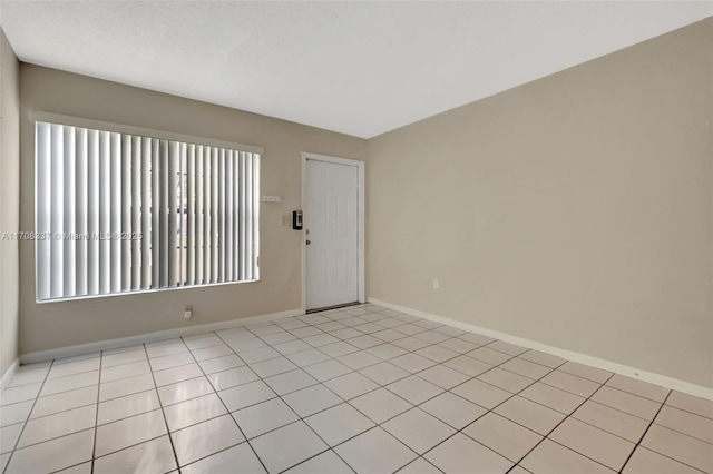 empty room featuring baseboards and light tile patterned flooring