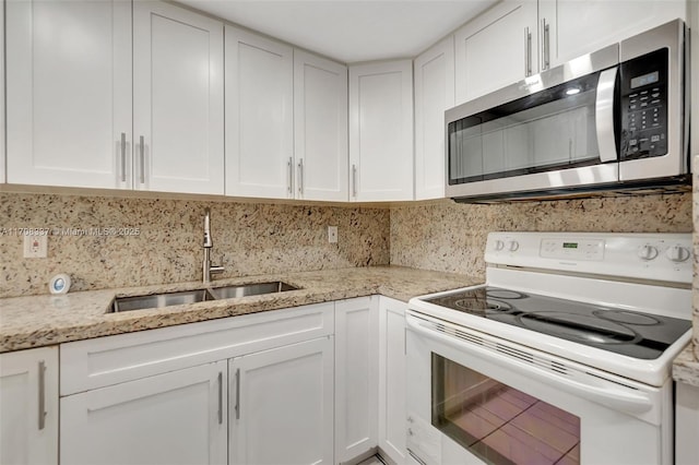 kitchen featuring stainless steel microwave, a sink, white electric range oven, and white cabinetry