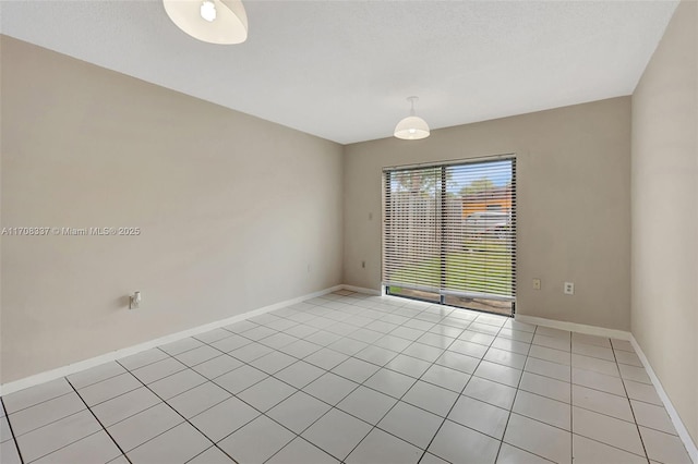 spare room with light tile patterned floors, a textured ceiling, and baseboards