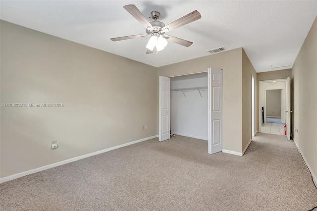 unfurnished bedroom with a ceiling fan, a closet, light carpet, and baseboards