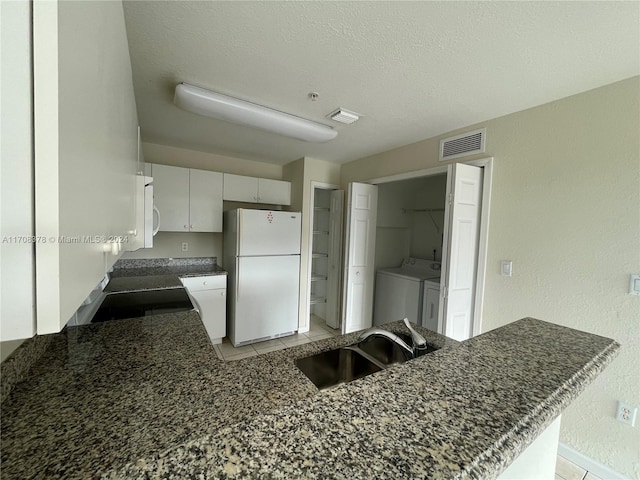 kitchen featuring white cabinetry, sink, independent washer and dryer, kitchen peninsula, and white appliances