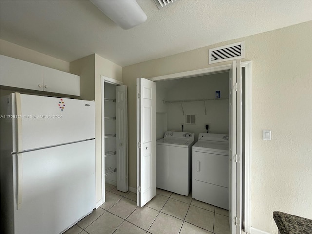 laundry room featuring light tile patterned floors, washing machine and dryer, and a textured ceiling