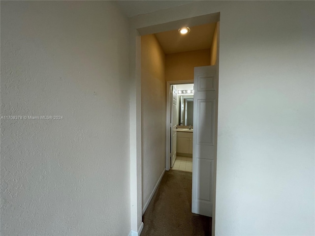 corridor featuring dark carpet and sink