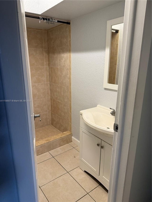 bathroom featuring a textured wall, a shower stall, tile patterned flooring, and vanity