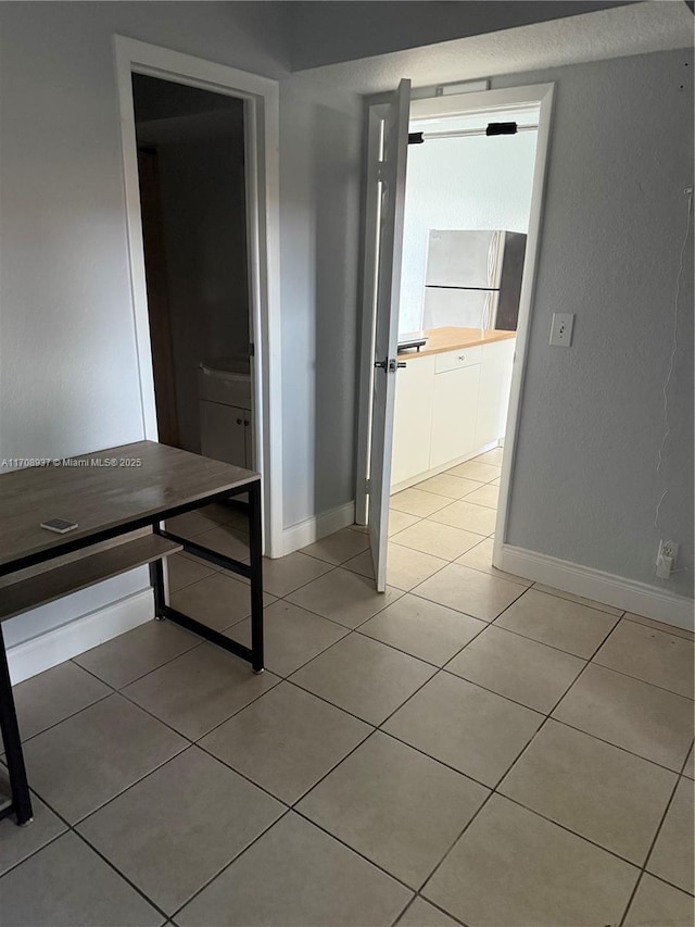 hallway featuring light tile patterned flooring and baseboards