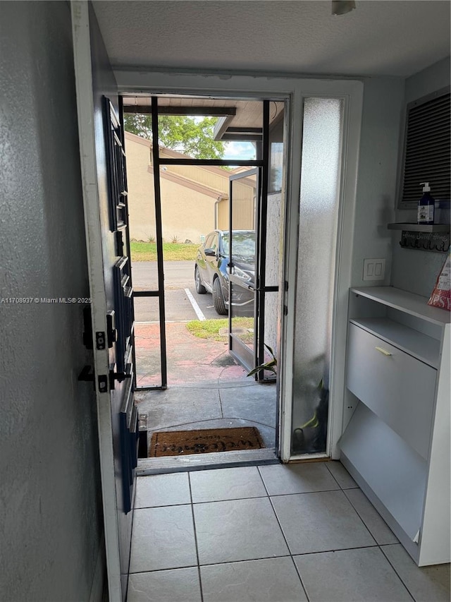 doorway with light tile patterned floors and a textured wall