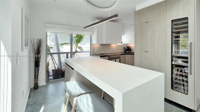 kitchen with a kitchen bar, wine cooler, modern cabinets, and concrete floors