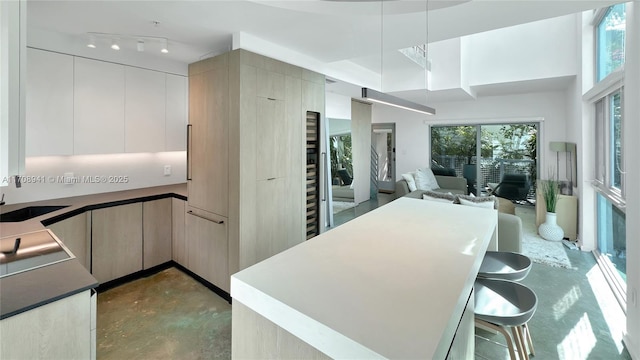 kitchen featuring dark countertops, modern cabinets, open floor plan, concrete floors, and a sink