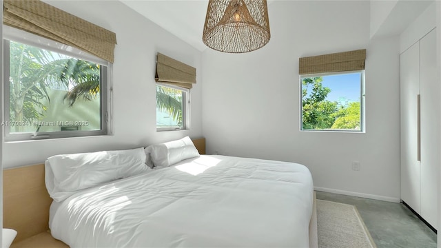 bedroom with concrete floors and baseboards