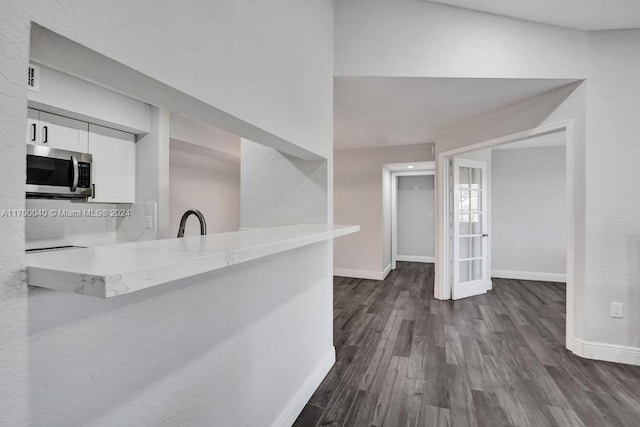 kitchen with dark hardwood / wood-style floors, sink, white cabinetry, and kitchen peninsula