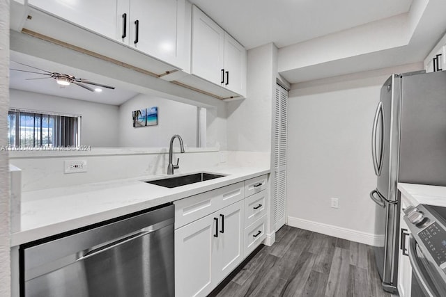 kitchen with white cabinets, sink, light stone countertops, appliances with stainless steel finishes, and dark hardwood / wood-style flooring