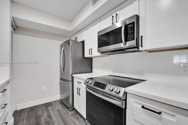 kitchen with white cabinets, light stone counters, wood-type flooring, and appliances with stainless steel finishes