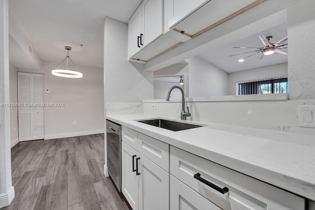 kitchen with stainless steel dishwasher, sink, decorative light fixtures, light hardwood / wood-style floors, and white cabinetry