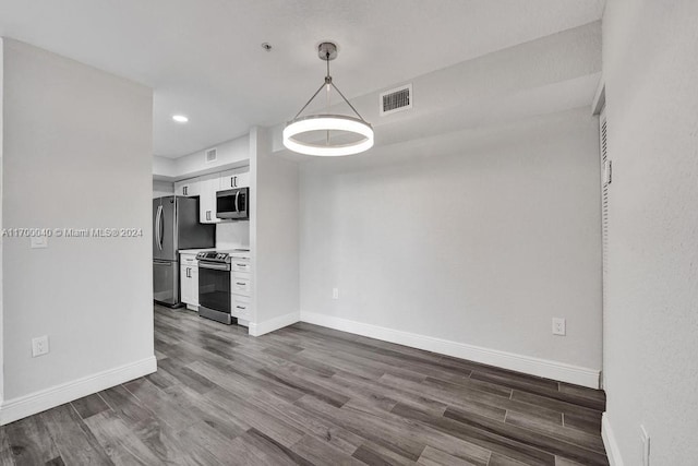 kitchen featuring decorative light fixtures, wood-type flooring, white cabinetry, and appliances with stainless steel finishes