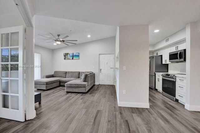 living room featuring vaulted ceiling, light hardwood / wood-style flooring, and ceiling fan