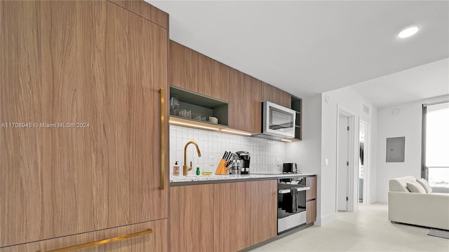 kitchen with electric panel, sink, decorative backsplash, light tile patterned floors, and stainless steel appliances