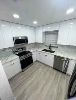 kitchen featuring appliances with stainless steel finishes, light hardwood / wood-style floors, white cabinetry, and sink