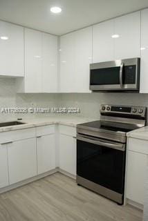 kitchen with light wood-type flooring, white cabinetry, and appliances with stainless steel finishes