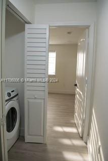 clothes washing area featuring washer / clothes dryer and light wood-type flooring