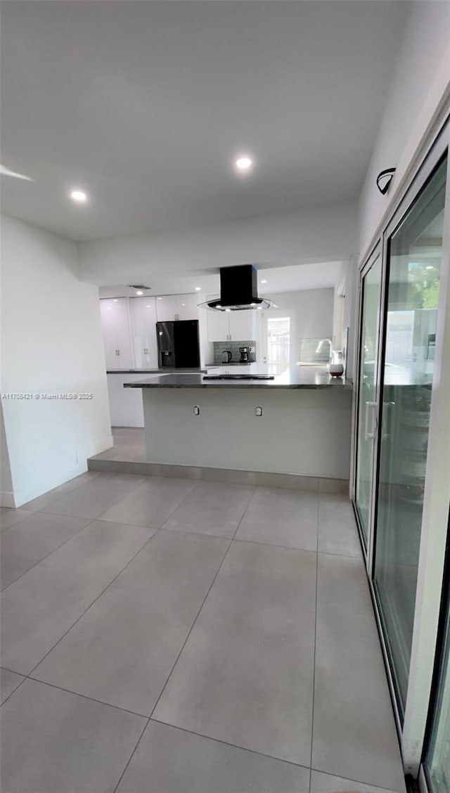 kitchen with island exhaust hood, white cabinets, black fridge, dark countertops, and modern cabinets