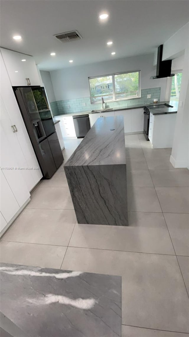 kitchen with visible vents, backsplash, appliances with stainless steel finishes, modern cabinets, and wall chimney exhaust hood