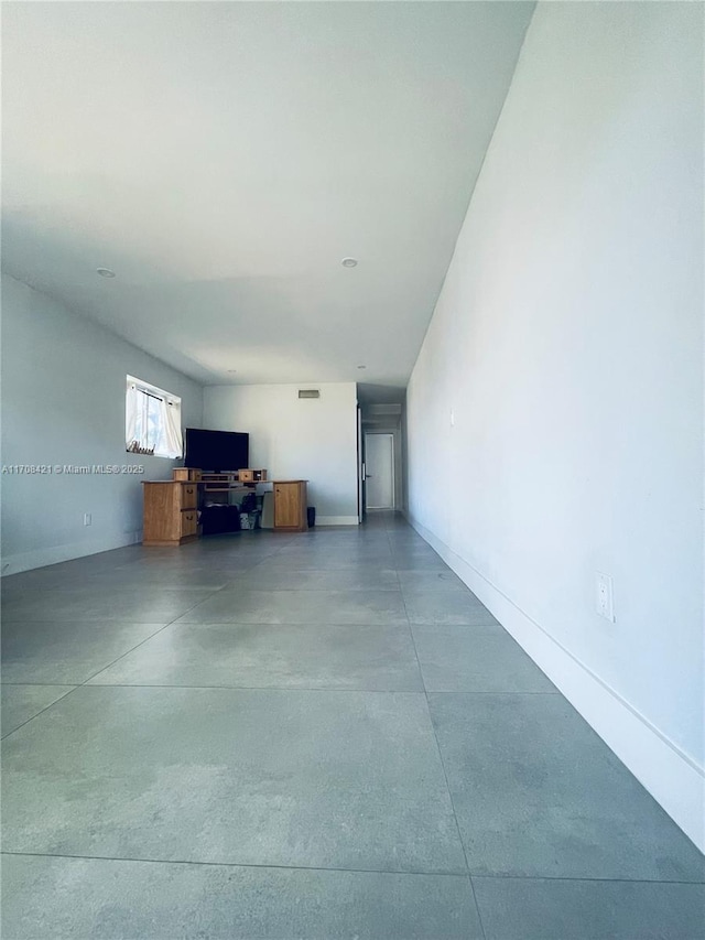 unfurnished living room with visible vents, finished concrete floors, and baseboards